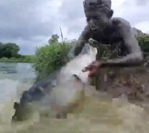 Seorang pemuda mancing ikan dengan tangan kosong